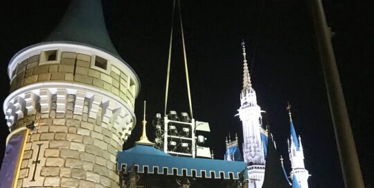 Castle turrets illuminated at night, dark sky.